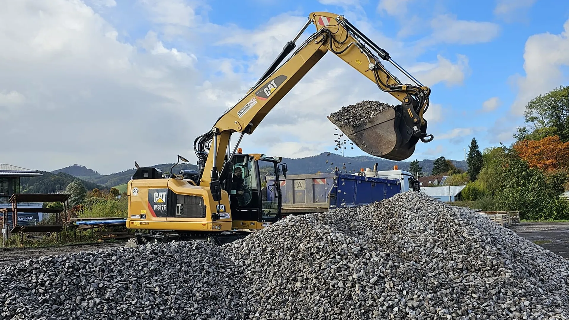 Mobilbagger auf einem Kieshaufen unter blauem Himmel