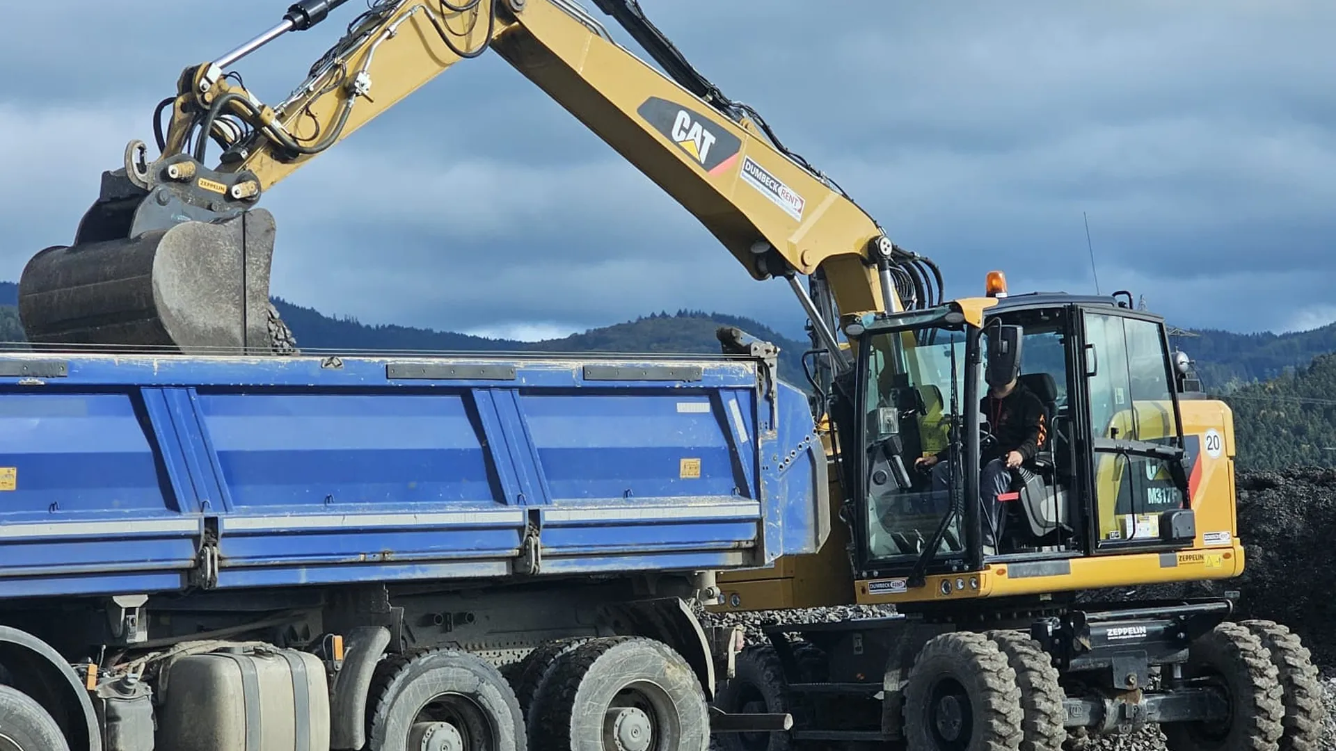 Mobilbagger belädt einen Kipplaster mit Schüttgut