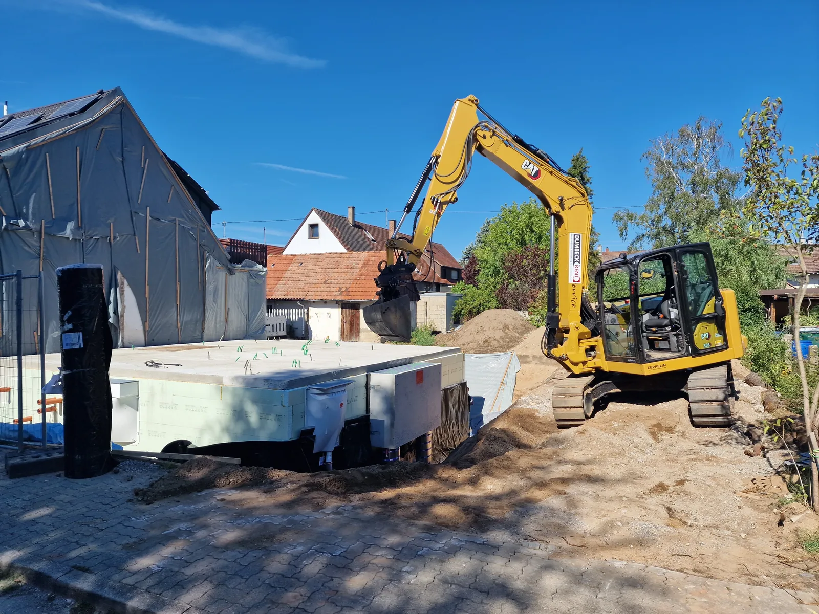Minibagger bewegt Material auf einer Baustelle neben einem Container